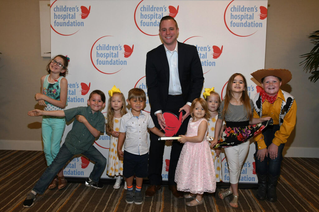Children and a man with an award at a Children's Hospital event.